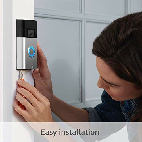 Person installing a video doorbell on a door frame.