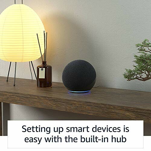 Smart speaker on a wooden shelf with a lamp and plant.