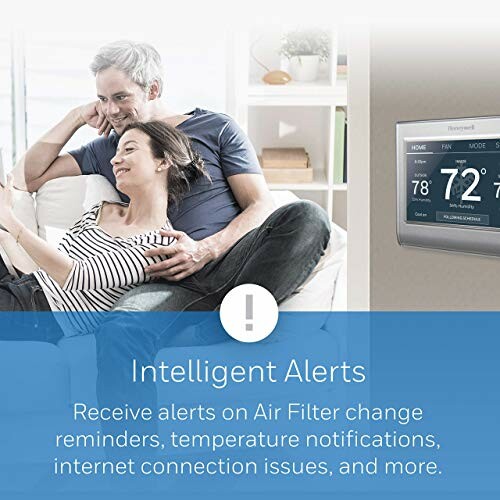 Couple relaxing with smart thermostat displaying intelligent alerts.