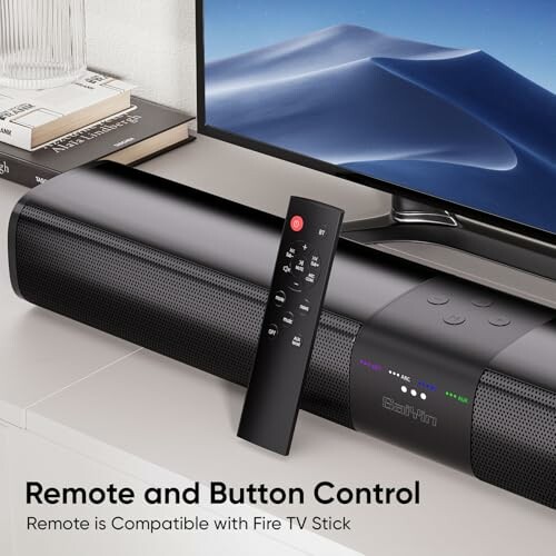 Soundbar with remote control on a table, compatible with Fire TV Stick.