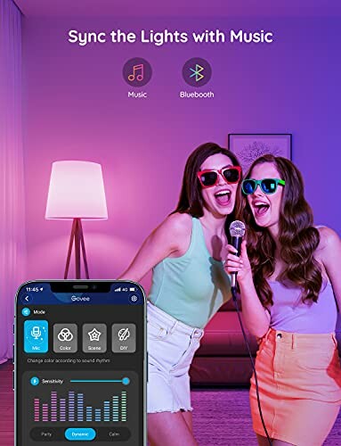 Two women singing with synced lights and app control interface on phone.